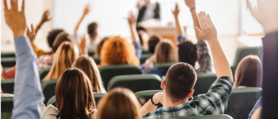 rear-view-of-large-group-of-students-raising-arms-during-a-class-at-picture-id1093523312